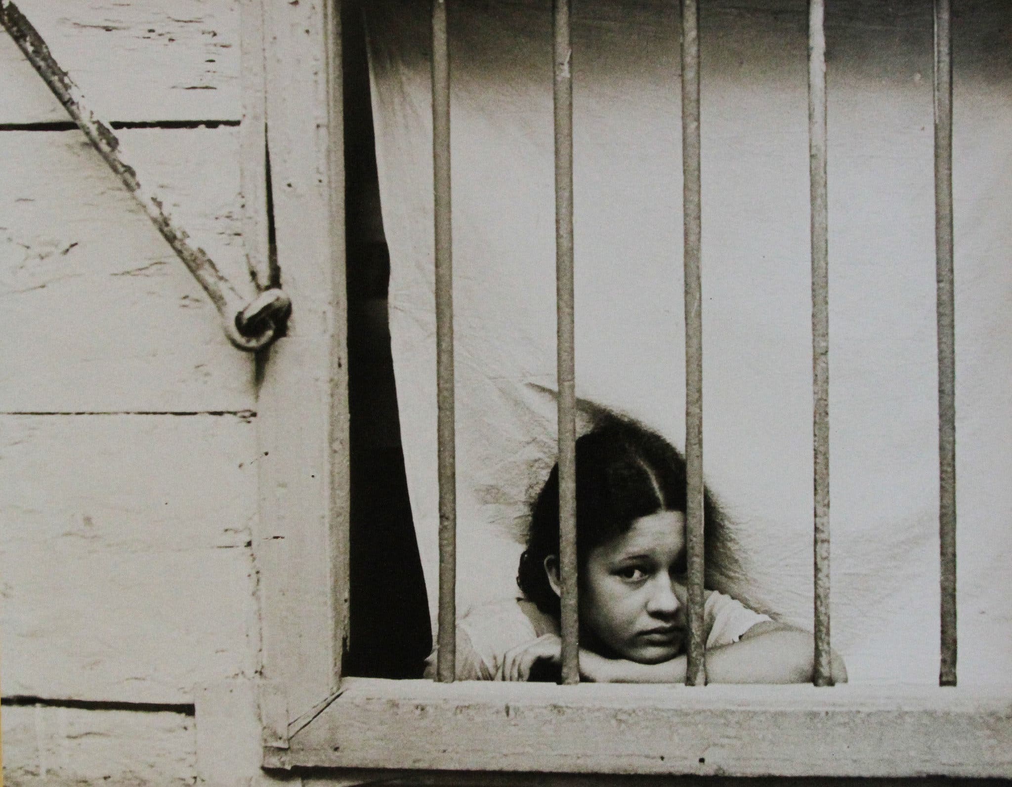 Cuban girl looking through window bars